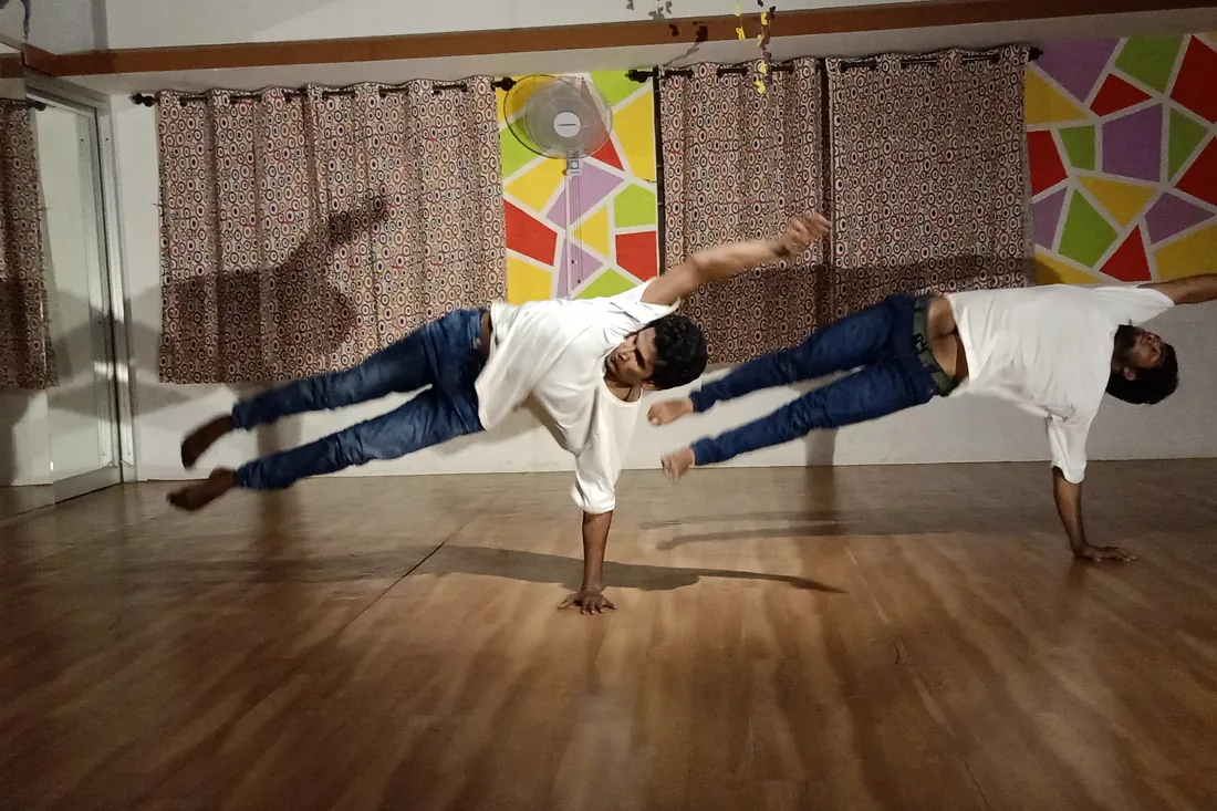 Two dancers holding a mid-air horizontal freeze during a studio training session
