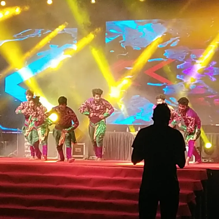 High-energy dance on a large event stage with concert lighting