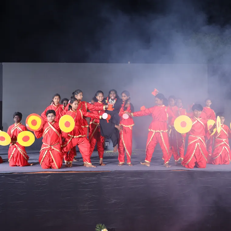 Group performance in red costumes with fans on a smoke-lit stage
