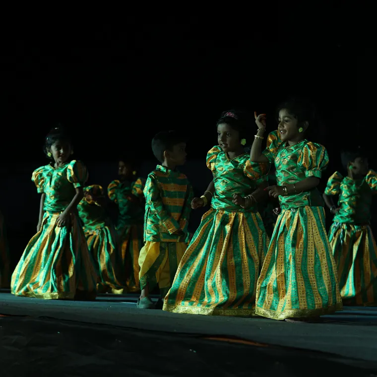 Folk dance group in green and gold costumes performing on stage