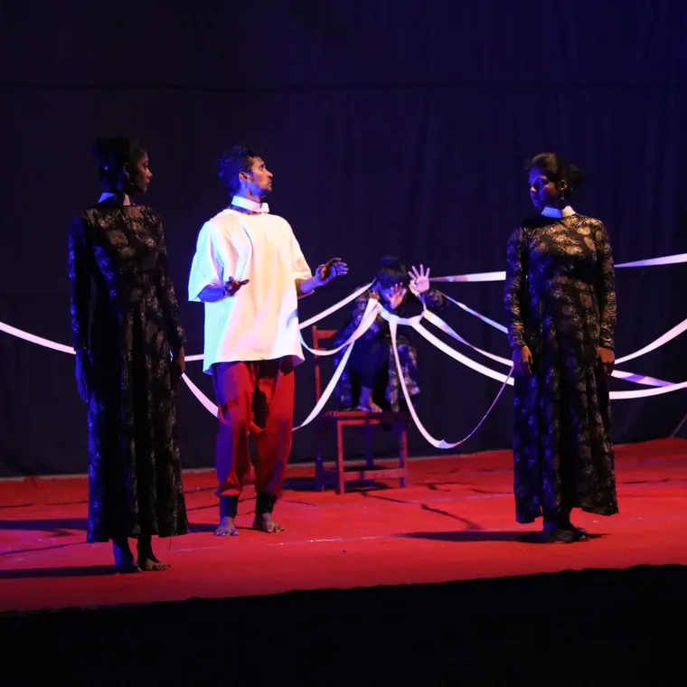 Theme-based stage production with ribbons under purple lighting